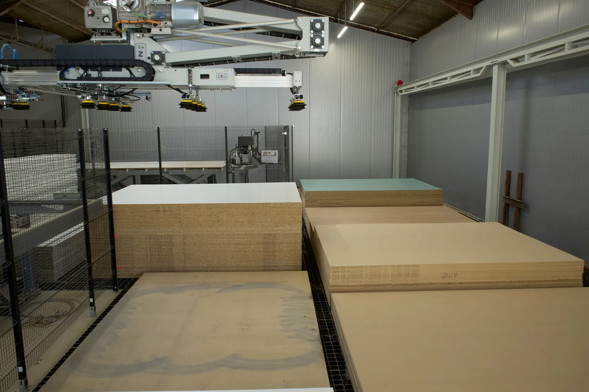 Piles de panneaux rangées à plat dans le magasin automatisé, sous le portique à ventouses
