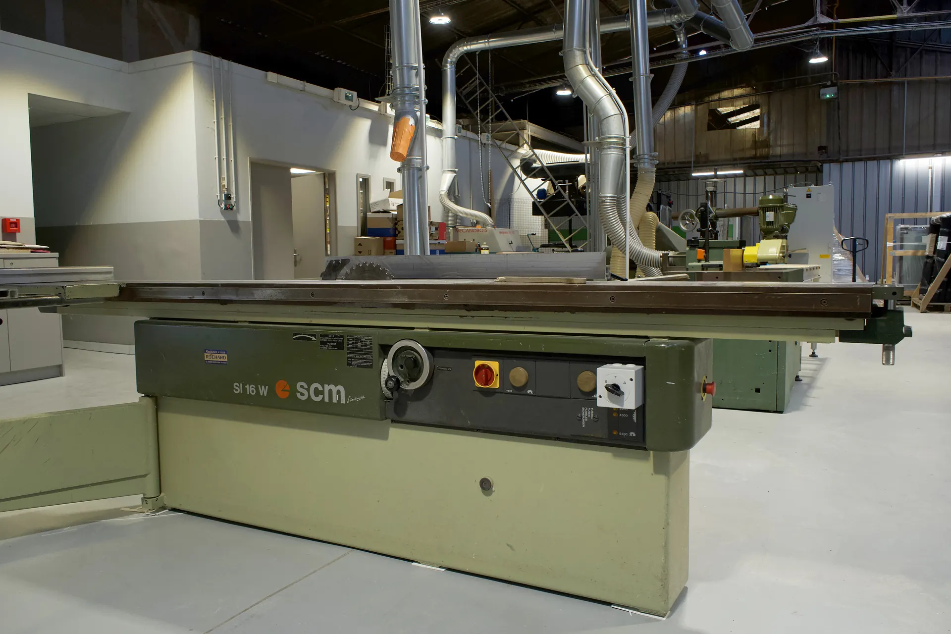 Scie à format de menuiserie avec son chariot coulissant, dans l'allée des machines à bois de l'atelier
